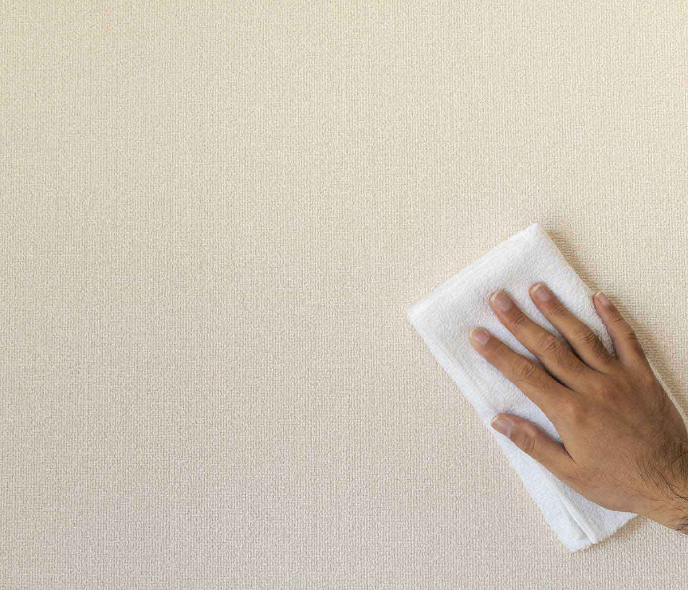 man cleaning wall to prepare for hanging wallpaper